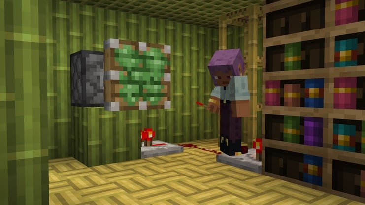 A player experimenting with Red Stone near some chiseled bookshelves in a house made of bamboo.